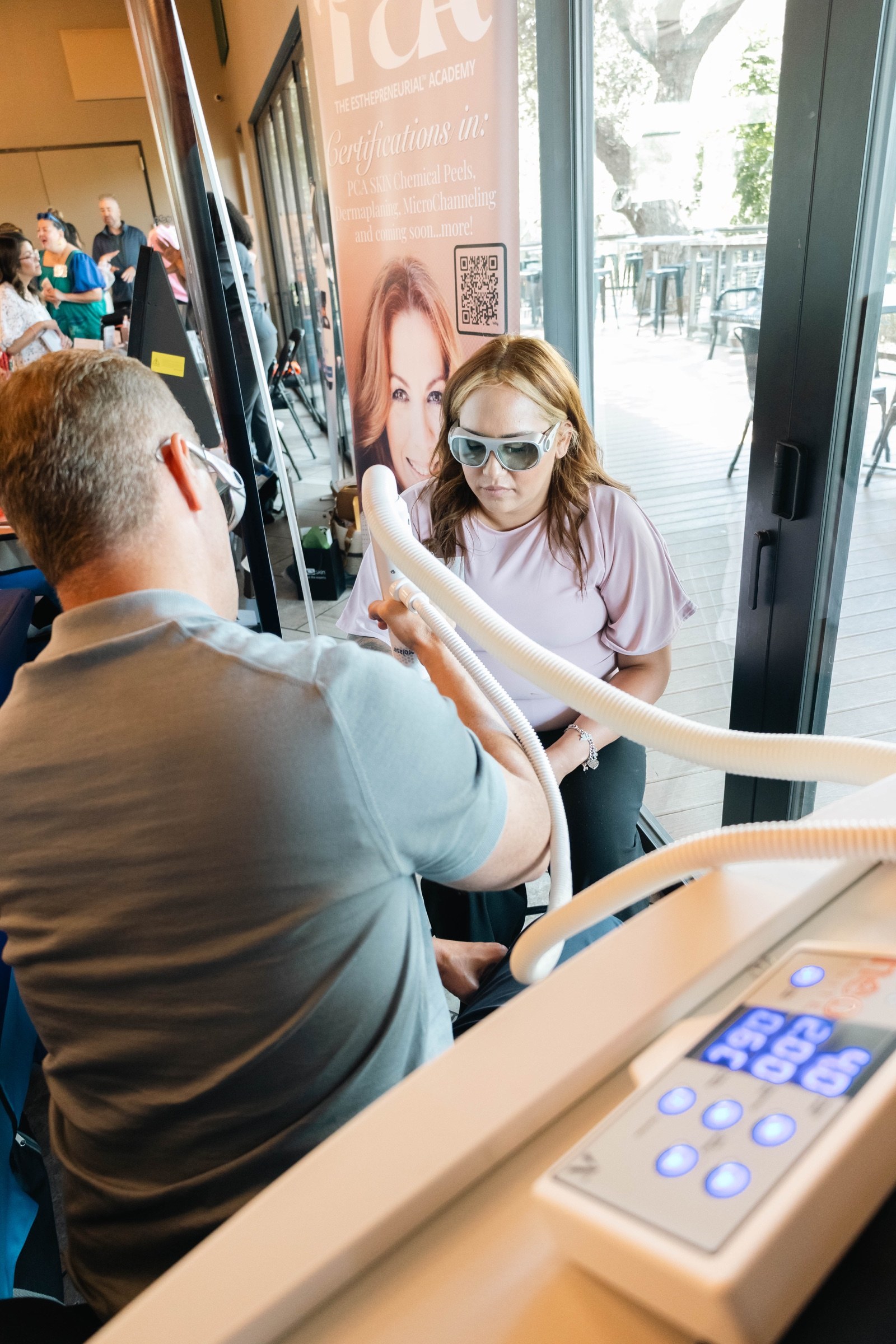 An attendee wearing protective glasses participates in an esthetic device demonstration